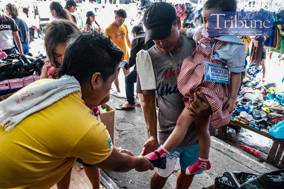 Edwin Ibanez, 55 years old, takes her daughter Precious, 4 years old, to buy new shoes with the help of her older sister Princess Nicole, 7 years old on July 18, 2024. PHOTO BY YUMMIE DINGDING